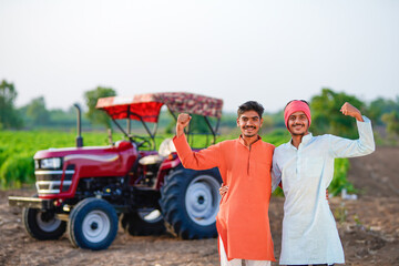 two young indian farmer standing together with tractor at field
