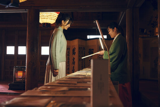 神社で巫女さんからお札を受け取る日本人女性