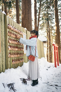神社で絵馬をかける日本人女性