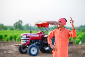 indian farmer standing with tractor at field