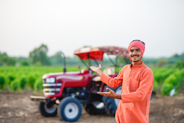 indian farmer standing with tractor at field