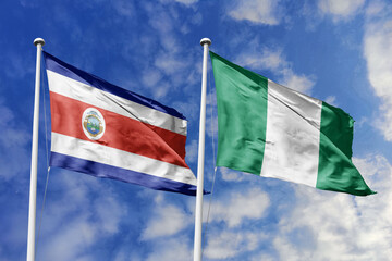 Costa Rica and Nigeria flags proudly waving against a vibrant blue sky, symbolizing international...