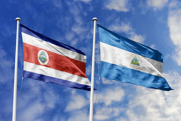 Costa Rica and Nicaragua flags proudly waving against a vibrant blue sky, symbolizing international...