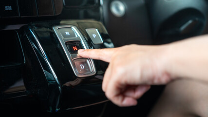 A driver is press on electrical A/T gear shifter button of the modern car. Transportation in action...