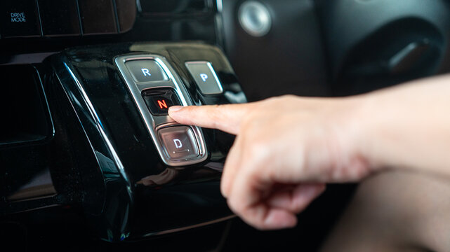 A driver is press on electrical A/T gear shifter button of the modern car. Transportation in action scene, selective focus.