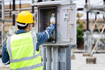 Engineer is working on high voltage power substation performing inspection and check of electrical...