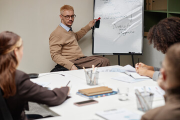 Caucasian young adult man with disability sitting in wheelchair presenting business strategy on...