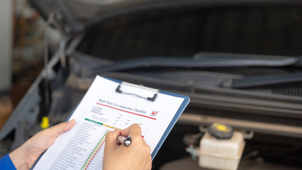 Action of a repairman is checking on multi-point checklist form during perform service the car parts. Industrial working scene, close-up and selective focus.