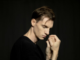 Close-up portrait of stylish handsome young man posing on dark background.