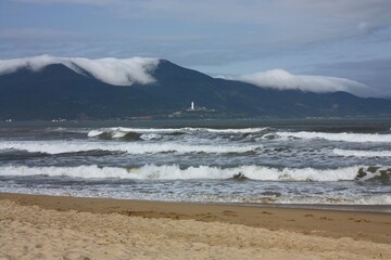 looking out  across the beach and waves in da nang in central vietnam at the lady buddha statue at linh ung pagoda on son tra peninsula on da nang bay