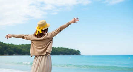 Woman in straw hat with arms outstretched embracing the ocean and sky