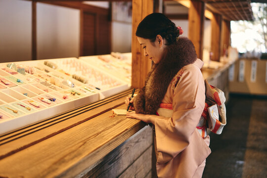 神社で絵馬に願い事を書く日本人女性