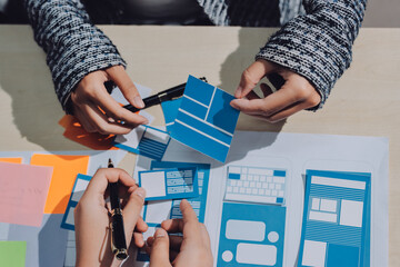 Group of young application developers analyzing uxui mobile app templates during a working meeting