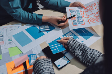 Group of young application developers analyzing uxui mobile app templates during a working meeting