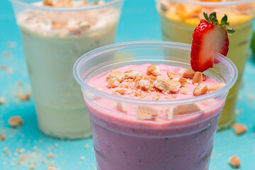 Strawberry, mango and lemon charlotte in plastic cups on light blue background