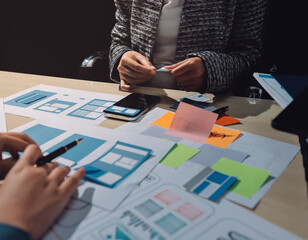 Group of young application developers analyzing uxui mobile app templates during a working meeting