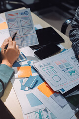 Group of young application developers analyzing uxui mobile app templates during a working meeting