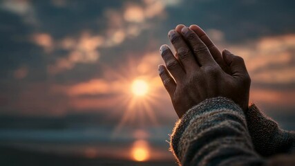 Hands clasped in prayer against a backdrop of a tranquil sunset sky, invoking serenity