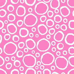 Seamless irregular circle pattern in white on pink background. Hand-drawn style abstract texture.