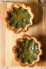 Closeup of Matcha and mochi Portuguese sweet dessert egg tart or Pastel de Nata on wooden board on...