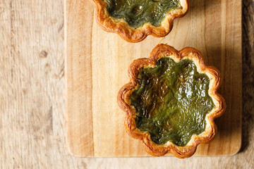 Closeup of Matcha and mochi Portuguese sweet dessert egg tart or Pastel de Nata on wooden board on...