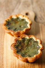 Closeup of Matcha and mochi Portuguese sweet dessert egg tart or Pastel de Nata on wooden board on...