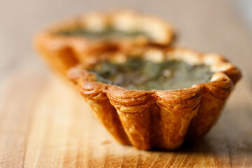 Closeup of Matcha and mochi Portuguese sweet dessert egg tart or Pastel de Nata on wooden board on...