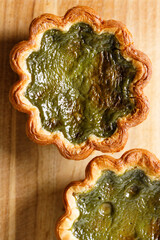 Closeup of Matcha and mochi Portuguese sweet dessert egg tart or Pastel de Nata on wooden board on...