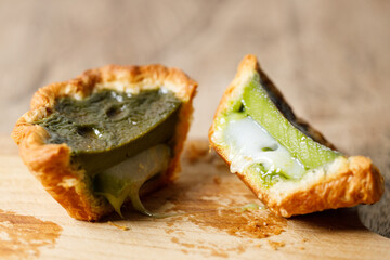 Closeup of Matcha and mochi Portuguese sweet dessert egg tart or Pastel de Nata on wooden board on...
