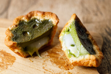 Closeup of Matcha and mochi Portuguese sweet dessert egg tart or Pastel de Nata on wooden board on...