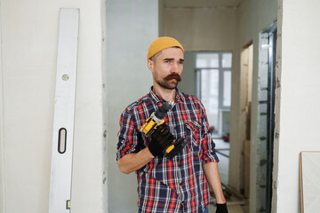 construction worker guy with a drill on a white wall background.master for an hour.