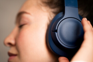 Side view close-up of young woman listening music in wireless headphones, female with closed eyes...