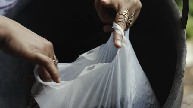 Close-up of a woman&rsquo;s hand placing roasted coffee beans into a white plastic in java indonesia .