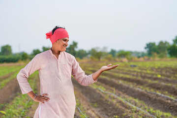 Young indian farmer standing at agriculture field