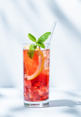 Refreshing cocktail with grapefruit, mint and ice in a glass on a light background with shadow