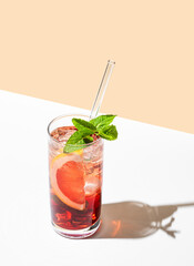 Refreshing cocktail with grapefruit, mint and ice in a glass on a white yellow background with...
