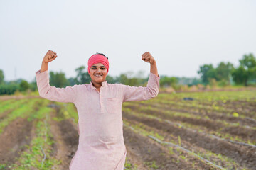 Young indian farmer standing at agriculture field