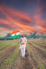 yong indian farmer holding indian flag standing at field