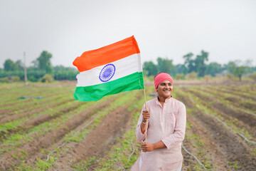 yong indian farmer holding indian flag standing at field