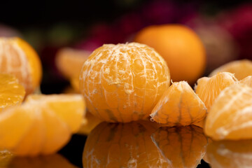 the reflection of an orange tangerine in a mirror surface close up, a peeled and juicy tangerine on a mirror