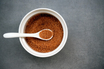 a white round bowl with brown sugar and a white spoon