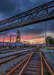 Marshalling yard at sunset with liquid transport train wagons and petrochemical industry on the background, Port of Antwerp, Belgium 