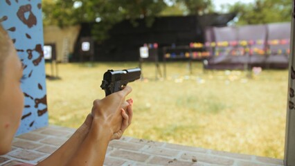 Woman shoots at shooting range with pneumatic gun. Outdoors entertainment for tourists in...