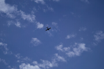 Small Airplane Flying in Blue Sky with Clouds