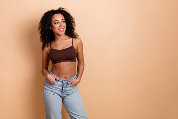 Stylish young woman in casual clothing posing in front of beige background, radiating confidence...
