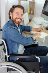 a man in a wheelchair writes with a pen