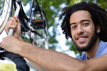 man fixing bicycle on to roof of car