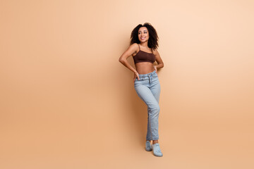 Young stylish woman in casual fashion posing on beige background with confident smile and relaxed...