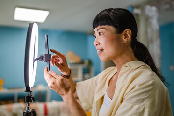 female japanese video blogger set up equipment and prepare for filming