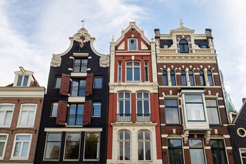 A close-up of three distinct historic gabled houses in Amsterdam, showcasing varied architectural...